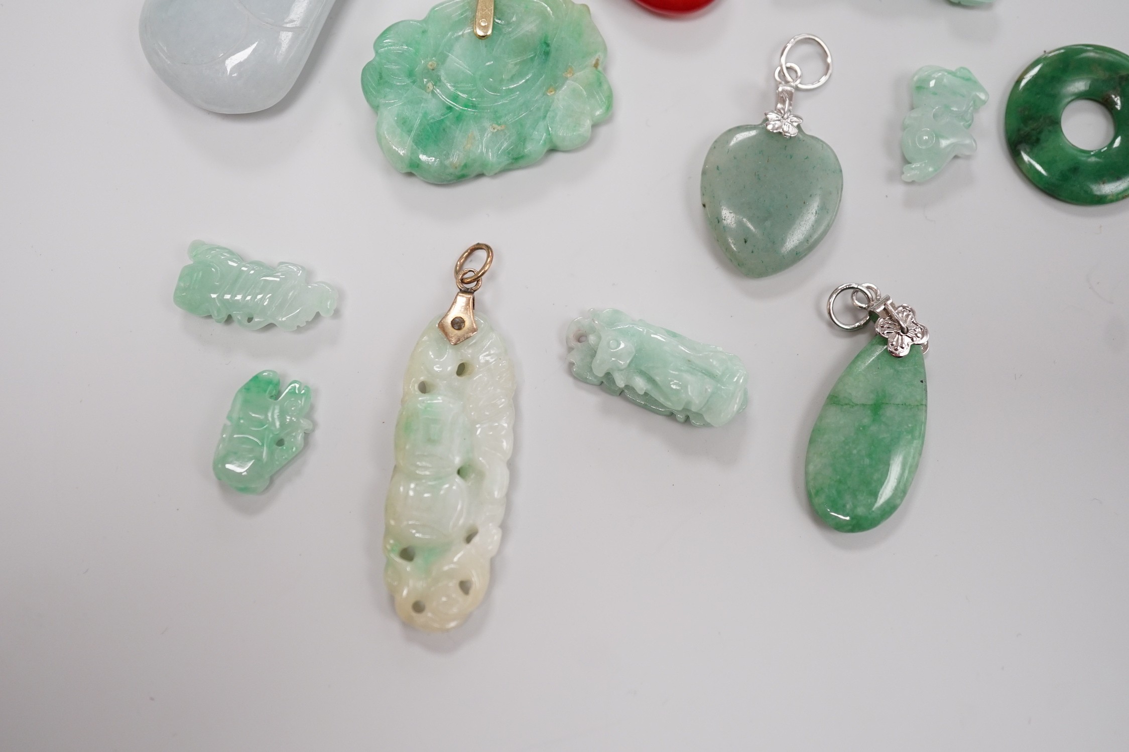 Twelve assorted carved jadeite items including five pendants, largest 40mm, a 14k mounted carnelian pendant and an unmounted pear cut simulated Tanzanite.